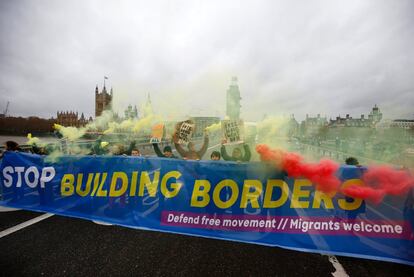 Manifestantes a favor de la migración sostienen bengalas y una pancarta durante una protesta en el puente de Westminster (Londres).