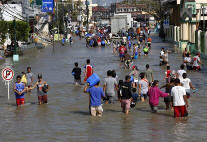 Varias personas caminan por las calles inundadas de Nabua (Filipinas) tras el paso del tifón Nock-Ten. 