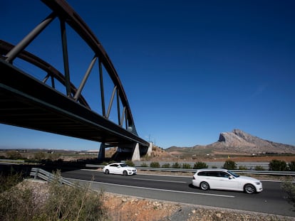 Varios coches circulan por la carretera A-92 a su paso por la localidad de Antequera, con la via del tren AVE arriba y la Peña de los Enamorados al fondo.