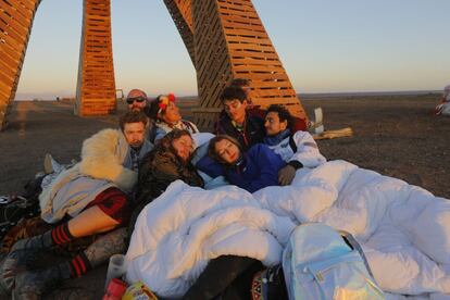 Los participantes que han estado de fiesta toda la noche miran el amanecer mientras se sientan debajo de la obra principal, llamada Sanclan, que después se quemará como símbolo de renovación espiritual.