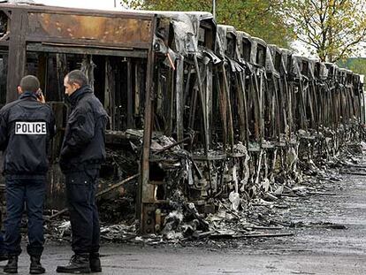 Un grupo de policías busca pistas en las cocheras de autobuses urbanos de Trappes, en las afueras de París, donde 27 vehículos fueron incendiados.