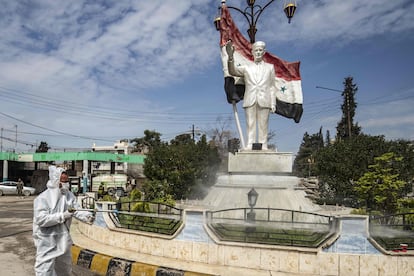 Un trabajador desinfecta una estatua del expresidente sirio Hafez el Asad, en la ciudad de Qamishli, en el nordeste de Siria, el pasado martes.