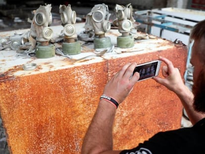 Un visitante toma una fotografía de máscaras antigás en una antigua base del ejército soviético, cerca de la Central Nuclear de Chernóbil.