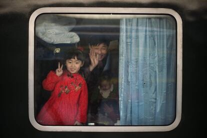 Algunos pasajeros saludan desde el interior de un tren a punto de partir, en la estación de Pekín (China). El gran movimiento de los chinos que viajan a casa para pasar el Año Nuevo Lunar con sus familias es a menudo descrito como la migración humana más grande del mundo.