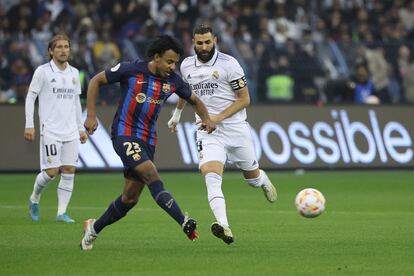 El defensa francés del Barcelona Jules Kounde pasa el balón ante la presión de Karim Benzema, durante la final.