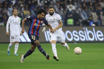 El defensa francés del Barcelona Jules Kounde pasa el balón ante la presión de Karim Benzema, durante la final.