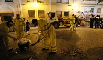 Un grupo de operarios de limpieza recoge la basura, escoltado por la policía.