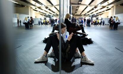 Las modelos pasan los ratos entre desfiles esperando en las puertas de los vestuarios de los diseñadores antes de las últimas pruebas.