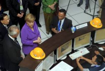 La canciller alemana, Angela Merkel (c), escucha a un funcionario en su visita al Sistema germano-indonesio de alerta temprana de tsunamis (GITEWS) en la Agencia de Meteorología, Clima y Geofísica (BMKG) en Yakarta, Indonesia.