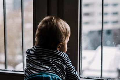 Un niño mira por la ventana.