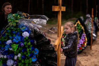 Daria Piven, de 33 años, mira a su hija Zlata, de 6, mientras visitan este lunes las tumbas de sus padres, Nadiya Miakushko y Volodímir Cherednichenko, que fueron asesinados por las tropas rusas a finales de marzo en Irpin, a las afueras de Kiev.