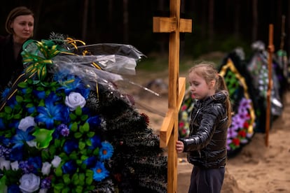 Daria Piven, de 33 años, mira a su hija Zlata, de 6, mientras visitan este lunes las tumbas de sus padres, Nadiya Miakushko y Volodímir Cherednichenko, que fueron asesinados por las tropas rusas a finales de marzo en Irpin, a las afueras de Kiev.