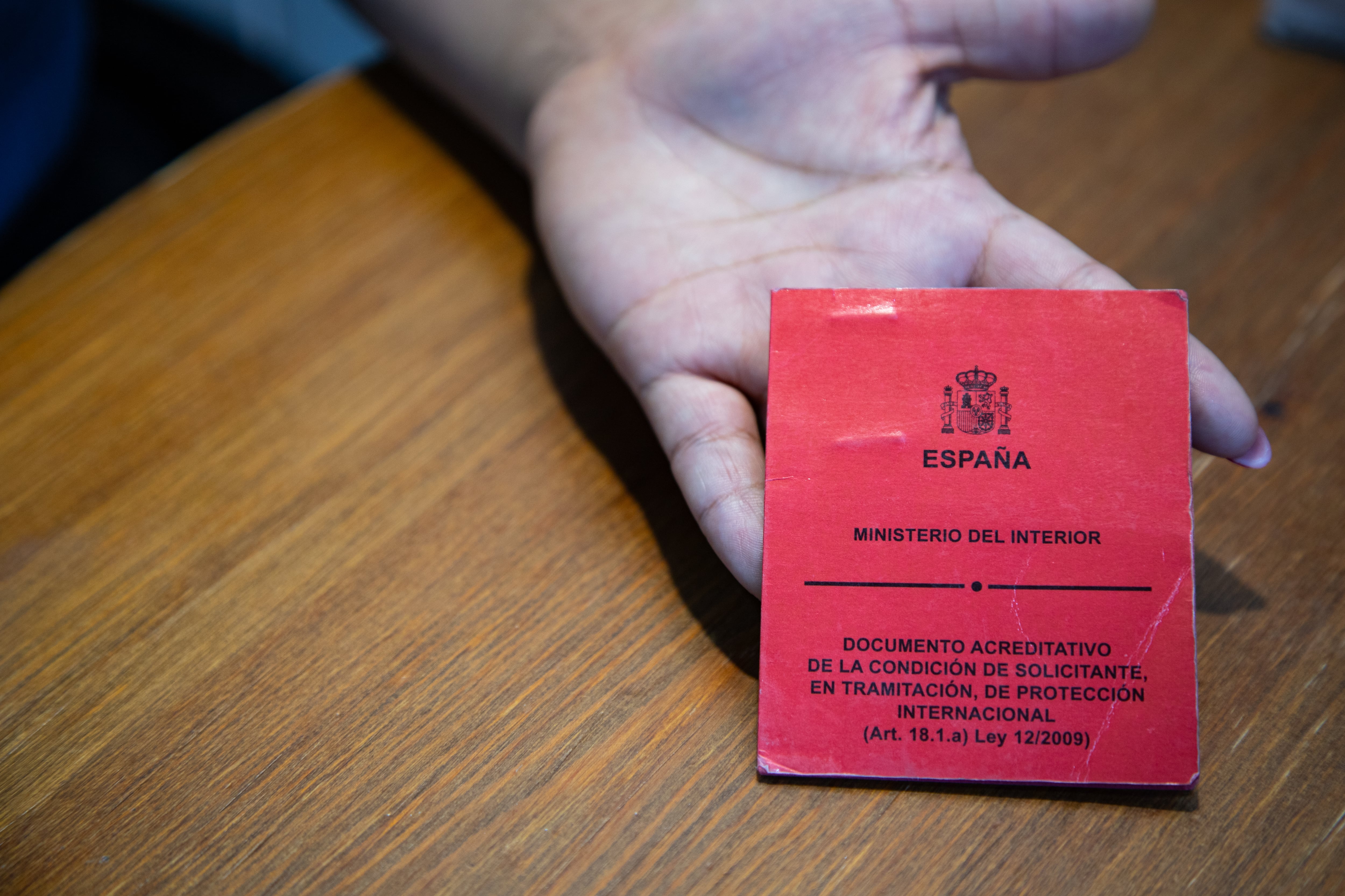 Diana muestra su documento de solicitante de asilo.