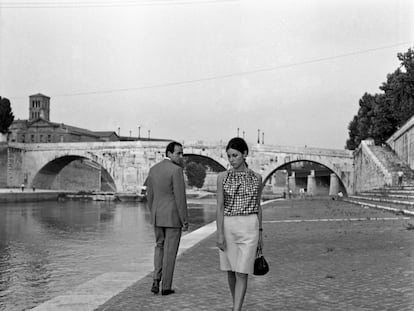 Un hombre y una mujer se dedican miradas tímidas junto a un río en Italia en los años sesenta, aproximadamente.