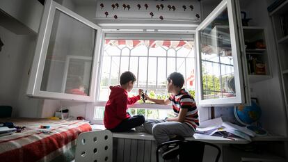 Dos niños  juegan en la ventana de su casa en Madrid, durante el confinamiento.