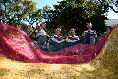 Torcedores alemães estendem uma bandeira gigante com as cores de seu país enquanto esperam que comece o jogo.