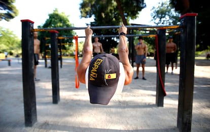 Un joven entrena en las barras del Ángel Caído, el parque de calistenia del parque del Retiro.