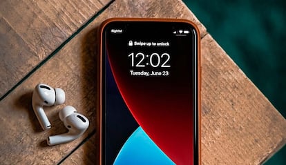 iPhone en una mesa con unos auriculares AirPods