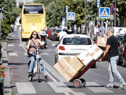 Una mujer circula con una bicicleta de Bicimad por el carril bici de la calle Mayor.