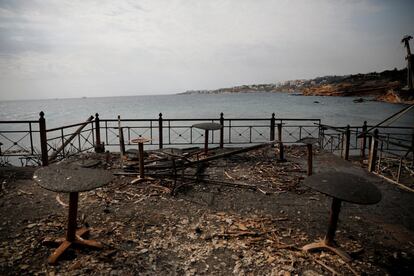 Mesas y sillas quemadas de un café junto al mar en la aldea de Mati.