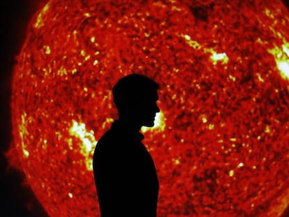 Un visitante pasa ante una imagen del sol en la exposición que invita a redescubrir el astro en Cosmocaixa, en Barcelona.