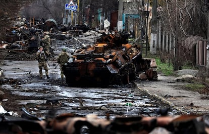 Soldados ucranios junto a un carro ruso destruido en la localidad de Bucha.