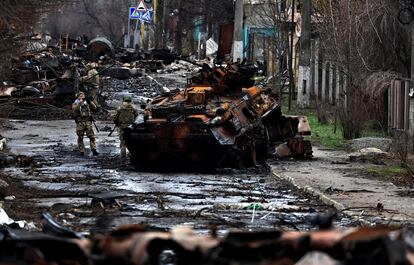 Soldados ucranios junto a un carro ruso destruido en la localidad de Bucha.