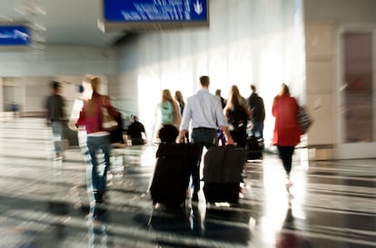 Pasajeros dirigiéndose con prisa hacia la puerta de embarque de su vuelo.