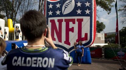 Fanáticos mexicanos se toman una foto frente al logo de la NFL.