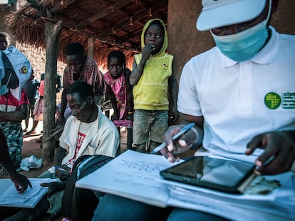 Rodeado por su mujer e hijos, Balança Manuel Sande rellena unos impresos que le han entregado los encuestadores del Centro de Investigación de Salud de Manhiça (CISM), en Mozambique, que colaboran con el Proyecto Bohemia.