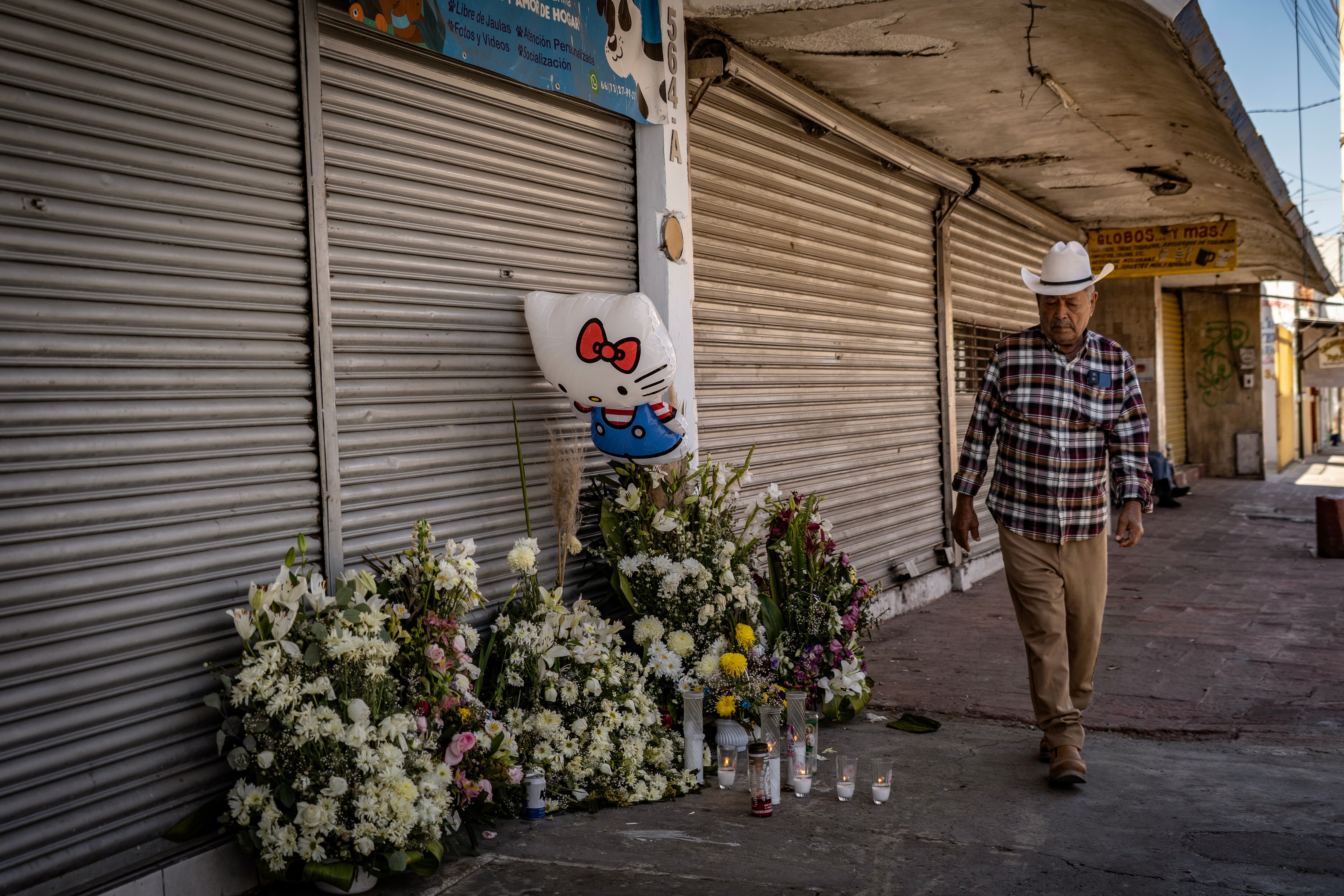 Un hombre frente a un altar colocado en memoria de cuatro mujeres que fueron atacadas por un hombre armado.