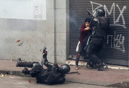 Un policía antidisturbios cae mientras uno de sus compañeros detiene a un manifestante durante las protestas en Quito, este martes.