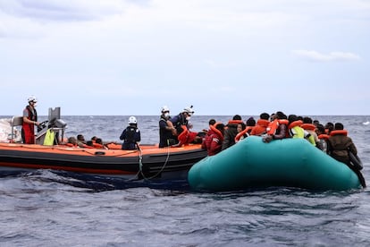 Un migrante embarca en la lancha semirrígida del 'Sea Watch 3' mientras otros esperan a ser rescatados de una precaria embarcación de goma en la que viajaban para llegar a Europa. Cuando los migrantes están agitados, es difícil atraer su atención para explicarles cómo se va a efectuar la operación de salvamento: todos tienen que tener un salvavidas y ponérselo correctamente, las mujeres y los niños subirán a bordo primero.