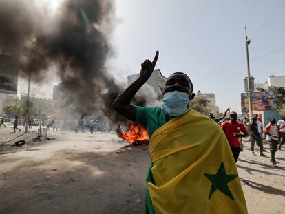 Un manifestante envuelto en una bandera senegalesa alza el dedo el cielo en medio de disturbios en Dakar, este viernes 9 de febrero.