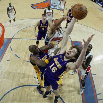 Gasol captura un rebote ante su compañero Odom y Dudley, de Charlotte.