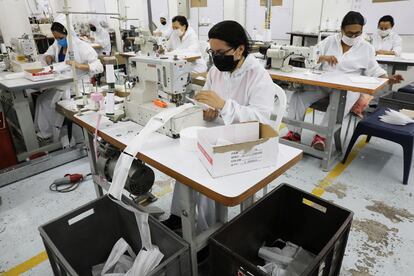 Trabajadores de una empresa textil fabrican mascarillas en Colombia.