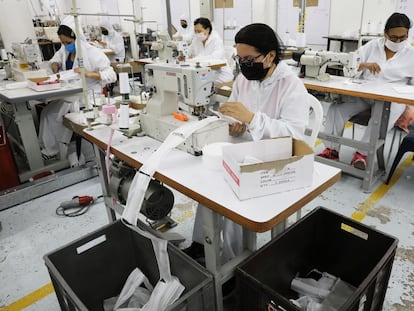 Trabajadores de una empresa textil fabrican mascarillas en Colombia.