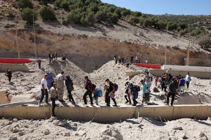 Civiles trasladan sus pertenencias entre los escombros de un ataque israelí en la frontera de Líbano y Siria, en el paso fronterizo de Masnaa.