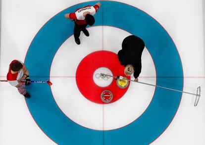 Torger Nergaard, de Noruega, y Benoit Schwarz, de Suiza, observan la medición durante la prueba de curling, el 17 de febrero.