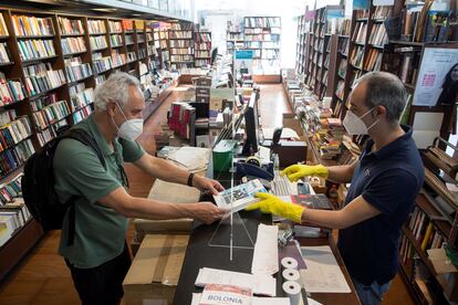 Un librero entrega un pedido a su cliente en Málaga tras el paso a la fase 1 de esa ciudad.