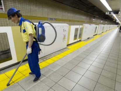 Un operario limpia el suelo del andén de una estación de metro de Tokio.