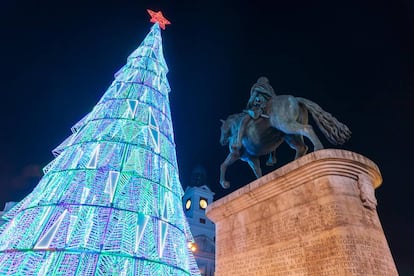 El abeto iluminado de la Puerta del Sol, escenario de las campanadas de Nochevieja, junto a la estatua de Carlos III.