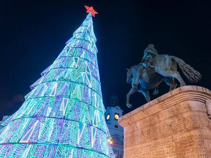 El abeto iluminado de la Puerta del Sol, escenario de las campanadas de Nochevieja, junto a la estatua de Carlos III.