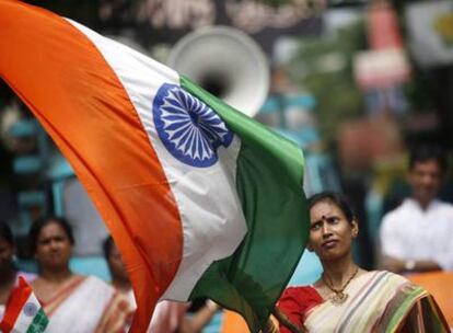 Una mujer india ondea la bandera de su país durante las celebraciones de los 60 años de la independencia.