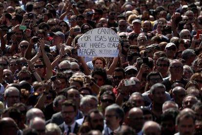 Una mujer sostiene un cartel que dice "Hoy canto por esas voces que habéis osado apagar" durante el minuto de silencio en la Plaza de Cataluña, en Barcelona.