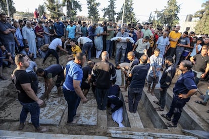 Palestinos ayudan durante el entierro de los miembros de la familia Al-Ahcazi, que perdieron la vida tras el impacto de un ataque israelí en su edificio de Rafah, al sur de la franja de Gaza, este martes.