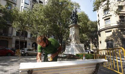 Un operario pinta uno de los bancos situados alrededor de la escultura de Rafael Casanovas. 