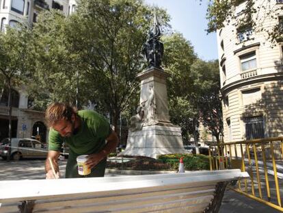Un operario pinta uno de los bancos situados alrededor de la escultura de Rafael Casanovas.