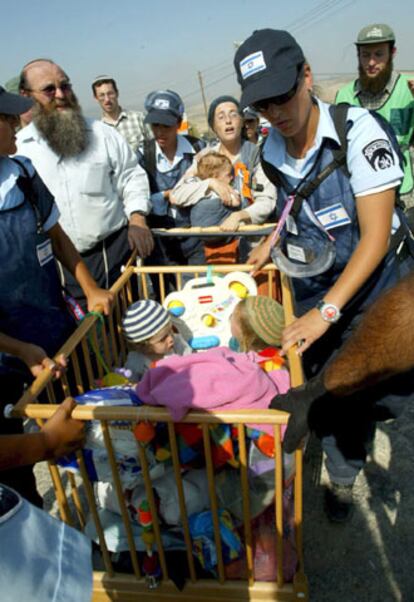 Soldados israelíes trasladan una cuna con dos niños del asentamiento de Sa-Nur.