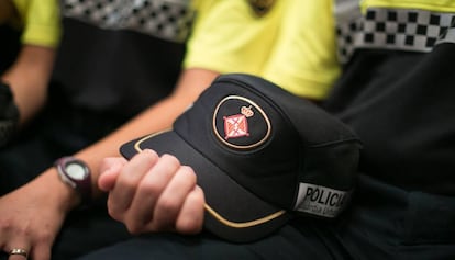 Un guardia urbano sostiene una gorra del cuerpo municipal.